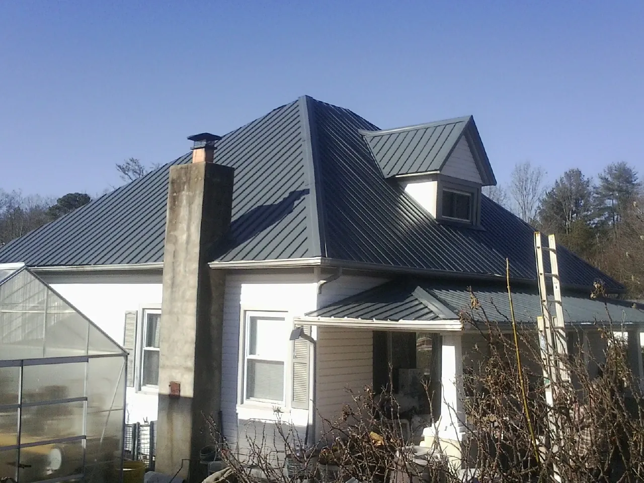 Dark blue standing seam metal roof on a white farmhouse with dormer — Slate & Tile Roof Repair by Roofing Brothers in Negley