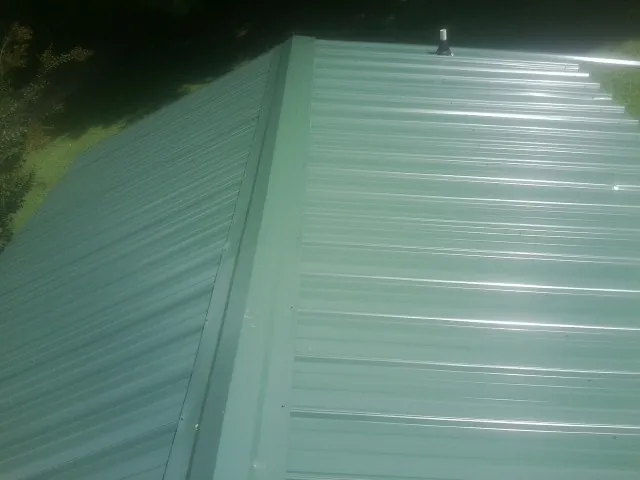 New green metal panels meeting at the ridge of a roof — Flat Roof Repair work by our crew in Negley