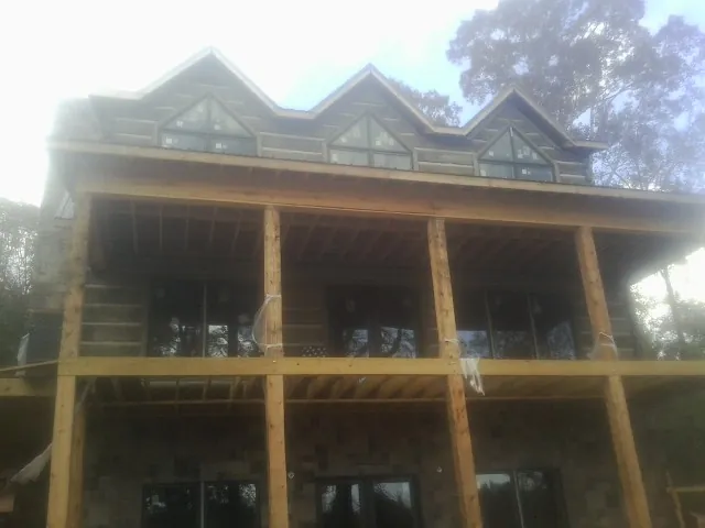 Dormers and porch framing on a large log home under construction — Roof Coating work by our crew in Negley