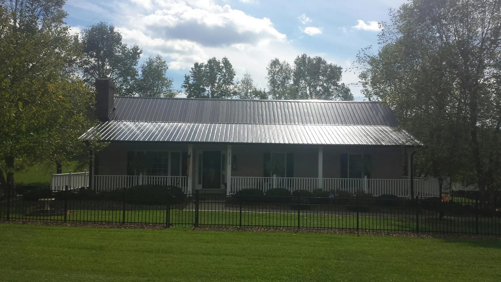Gray metal roof on a brick ranch with a full width front porch — Gutter Guard Installation work by our crew in Negley