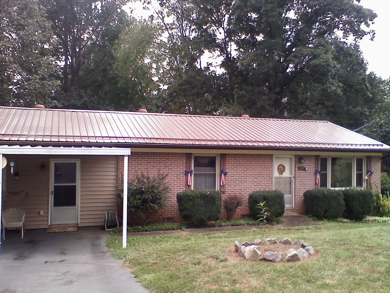 Bronze metal roof and carport on a brick ranch home — Roof Repair work by our crew in Negley