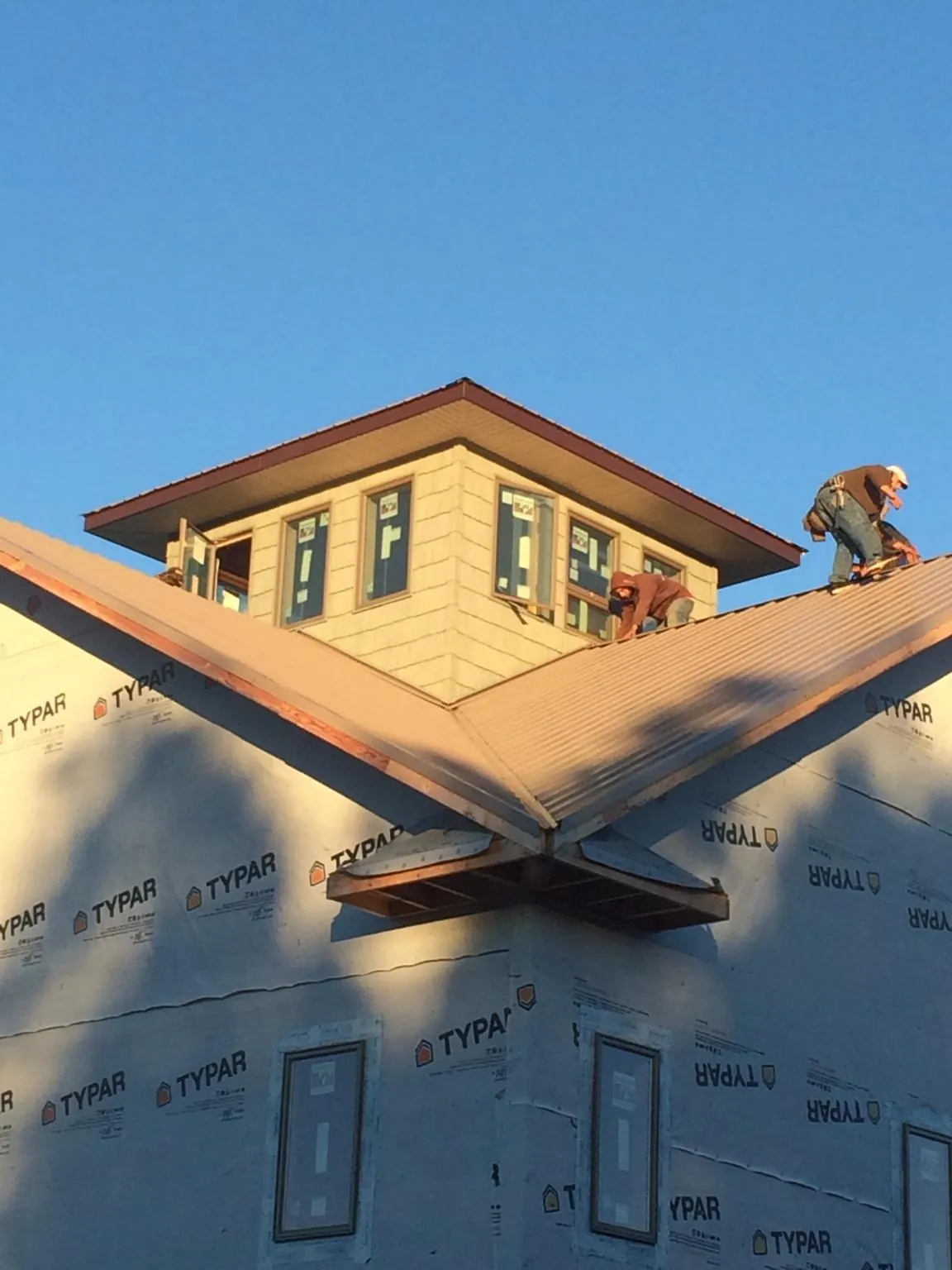 Roofers working around a rooftop cupola on a new metal roof at sunset — Roof Waterproofing in Negley by Roofing Brothers